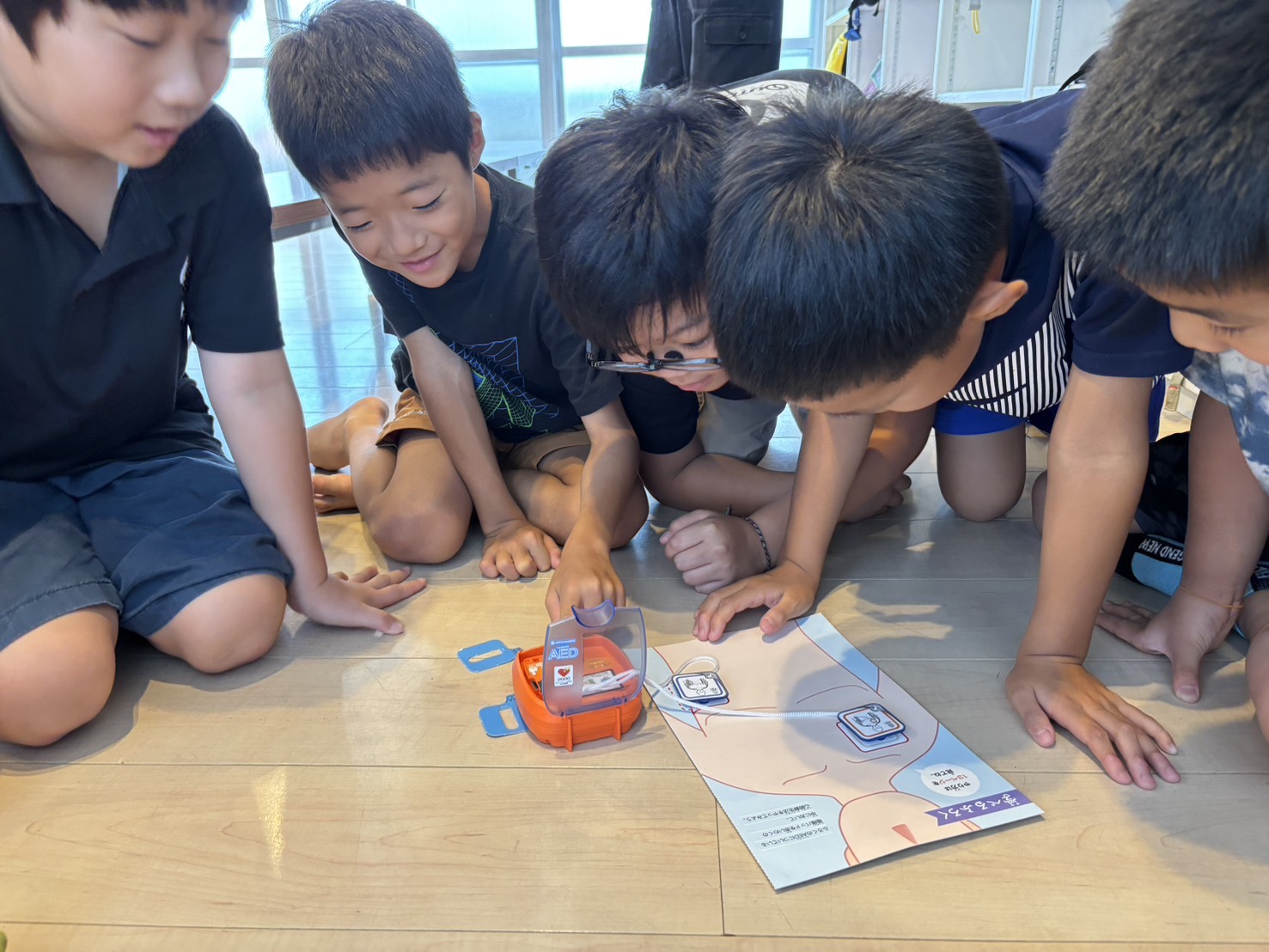 友だちとAEDの使い方を学ぶ子どもたち