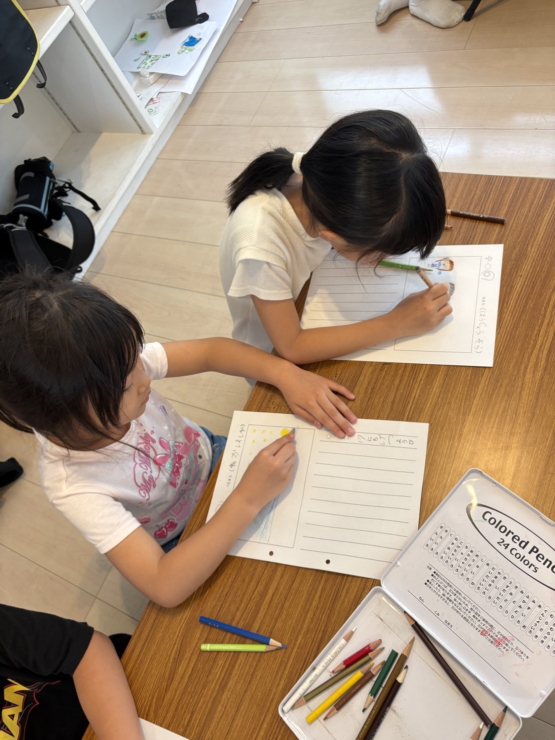 色鉛筆を使い、机に向かって絵やことばをかく子どもたち