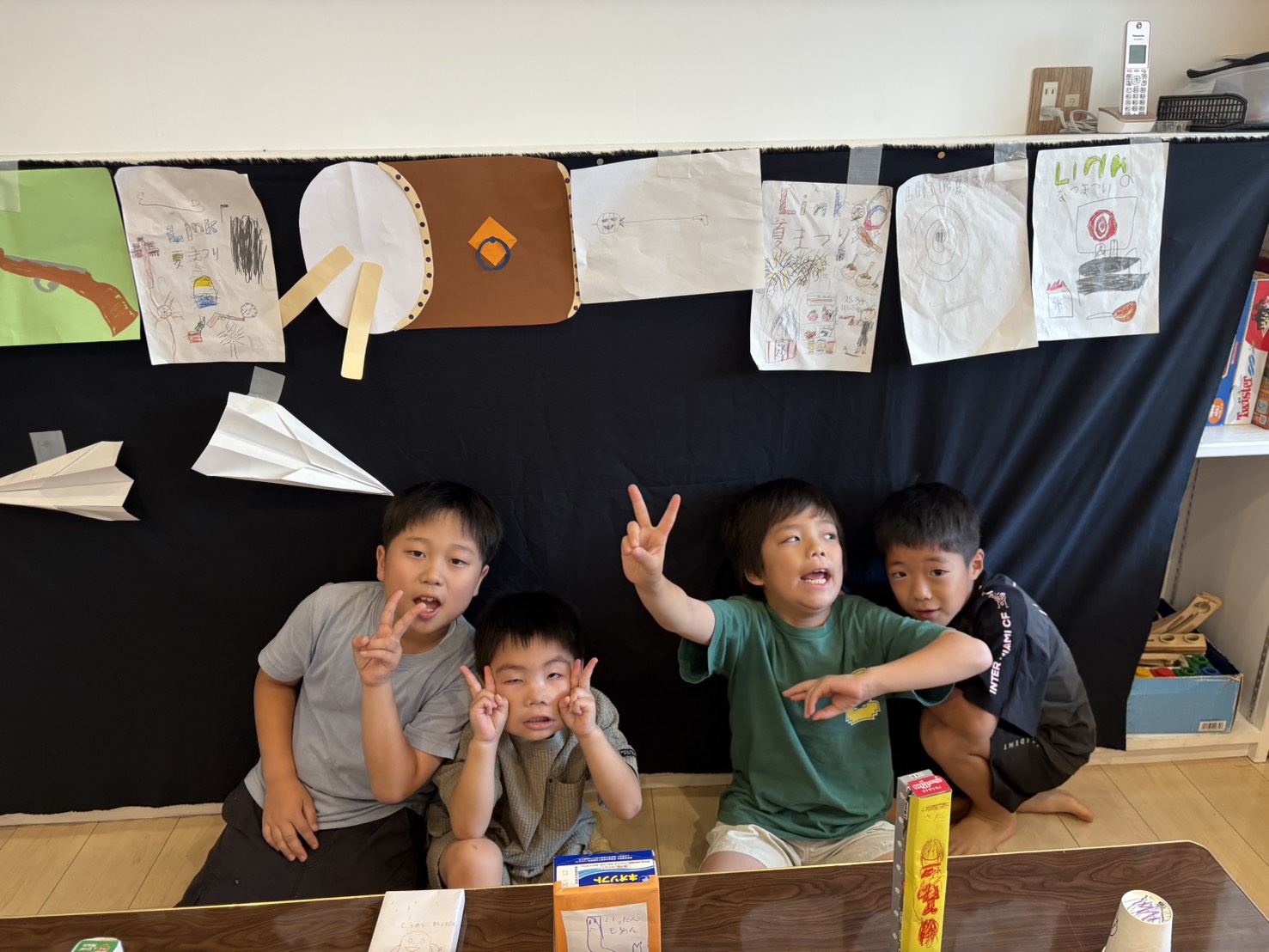 自分たちで描いた夏祭りの看板の前で、ポーズをとる子どもたち