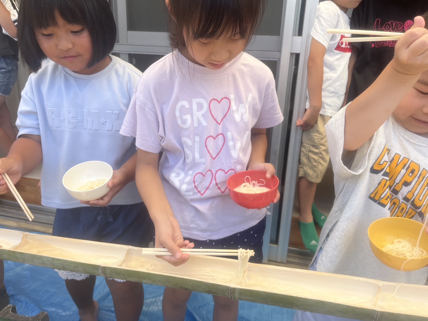 竹を流れるそうめんを、お箸でつかむ子どもたち